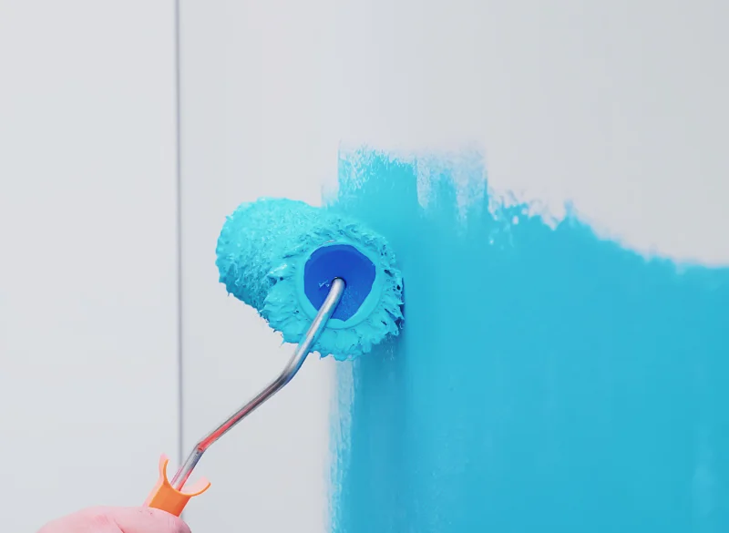Application d’une peinture turquoise au rouleau sur un mur intérieur